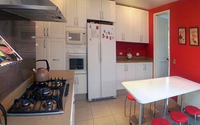Muebles de cocina85 a medida con puertas termolaminadas en pvc blancas y cubierta de Silestone crema minerva en Lo Barnechea, Santiago de Chile
